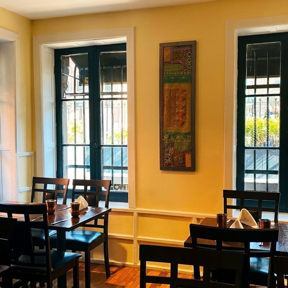 Cozy dining room with yellow walls, dark wooden tables and chairs, and large windows with natural light.